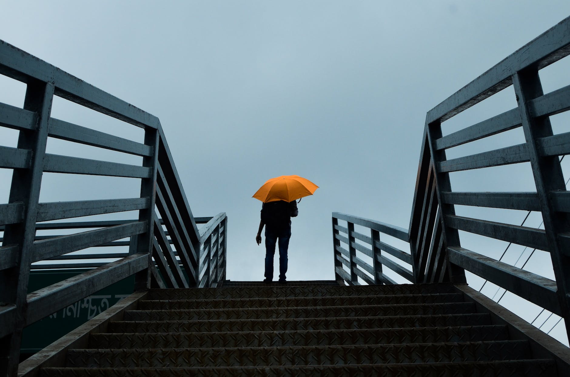 person holding umbrella standing above stairs