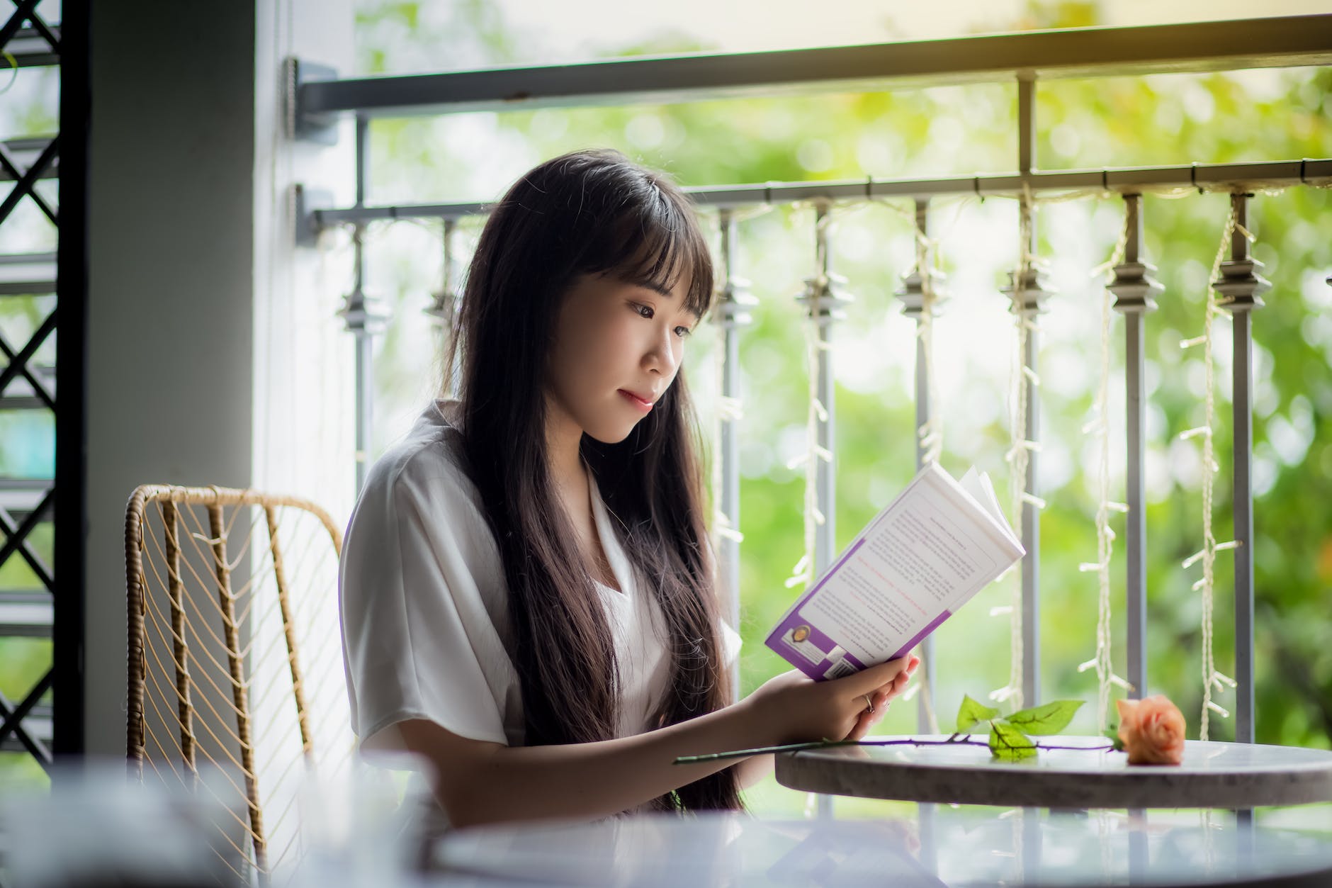 woman sitting on chair beside table reading a book