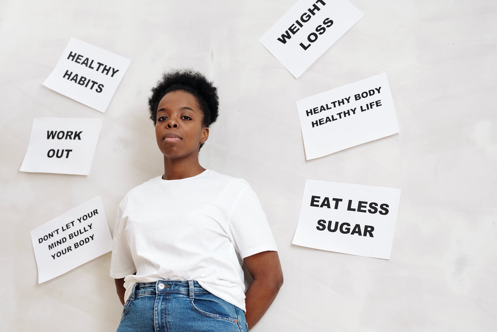 woman standing beside a wall with posted papers on healthy living