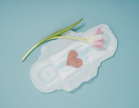 feminine hygiene pad and pink tulip placed on blue background