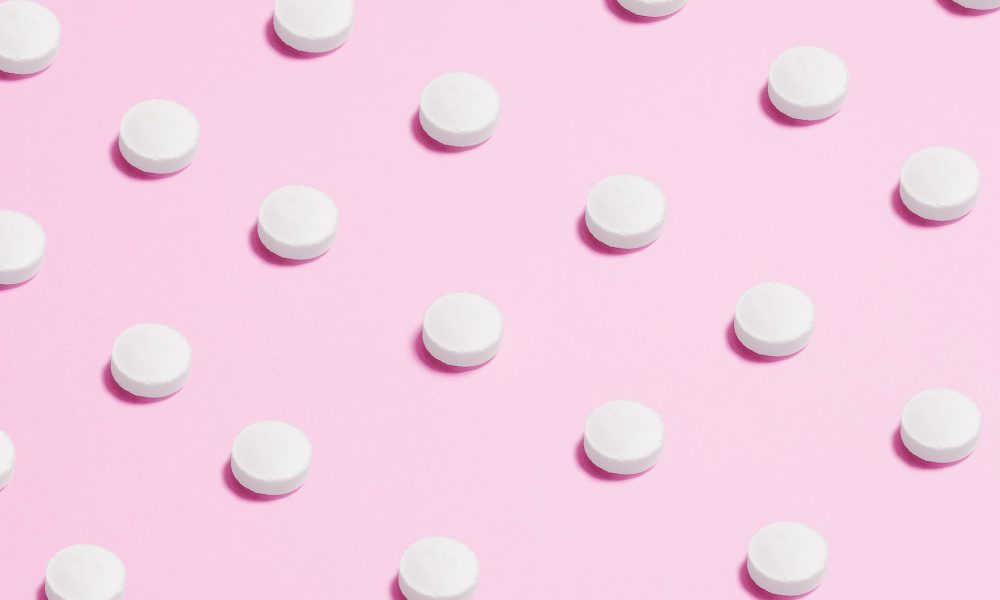 white round capsule on pink background close up photography