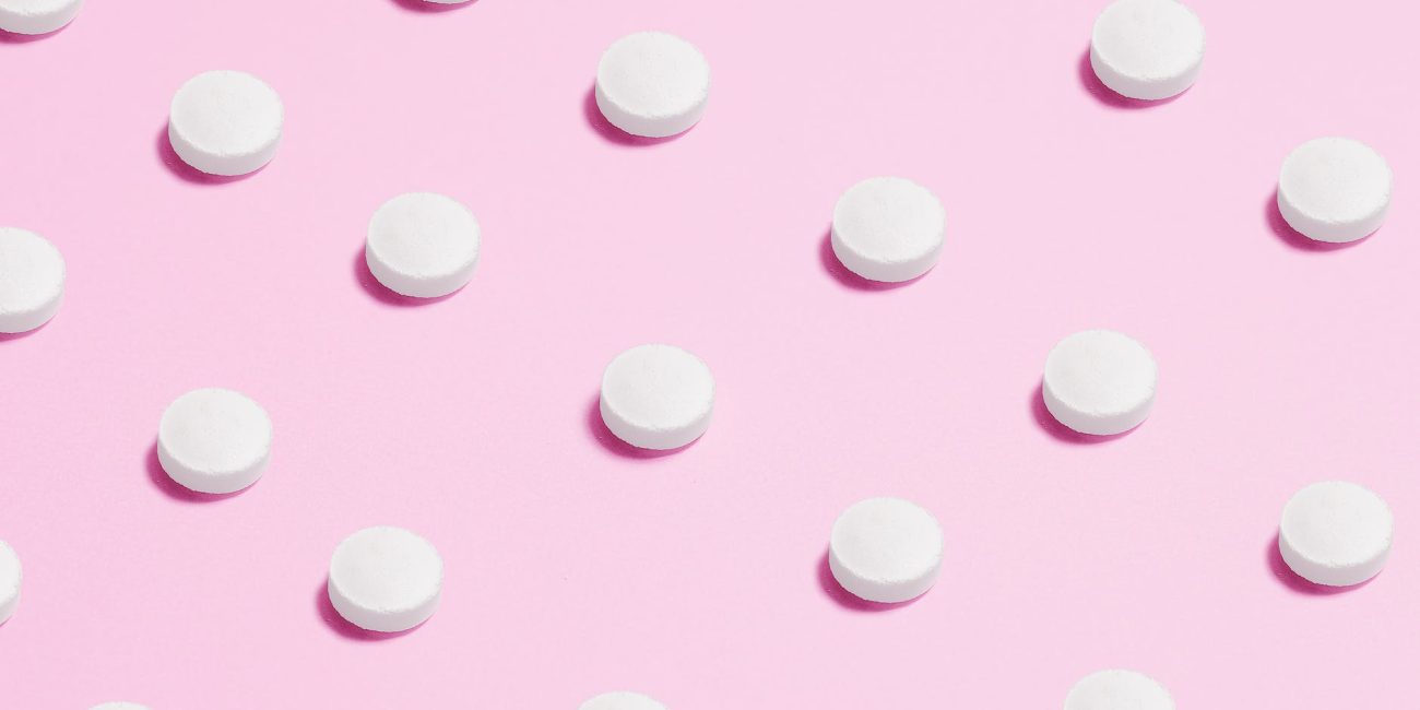 white round capsule on pink background close up photography