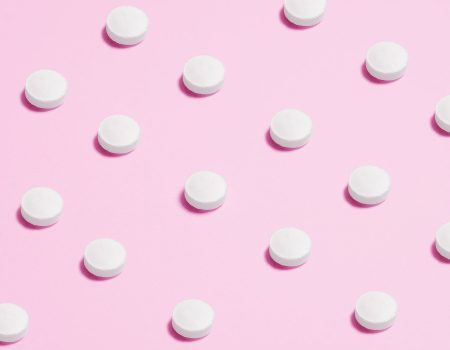white round capsule on pink background close up photography