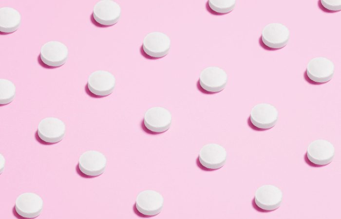 white round capsule on pink background close up photography