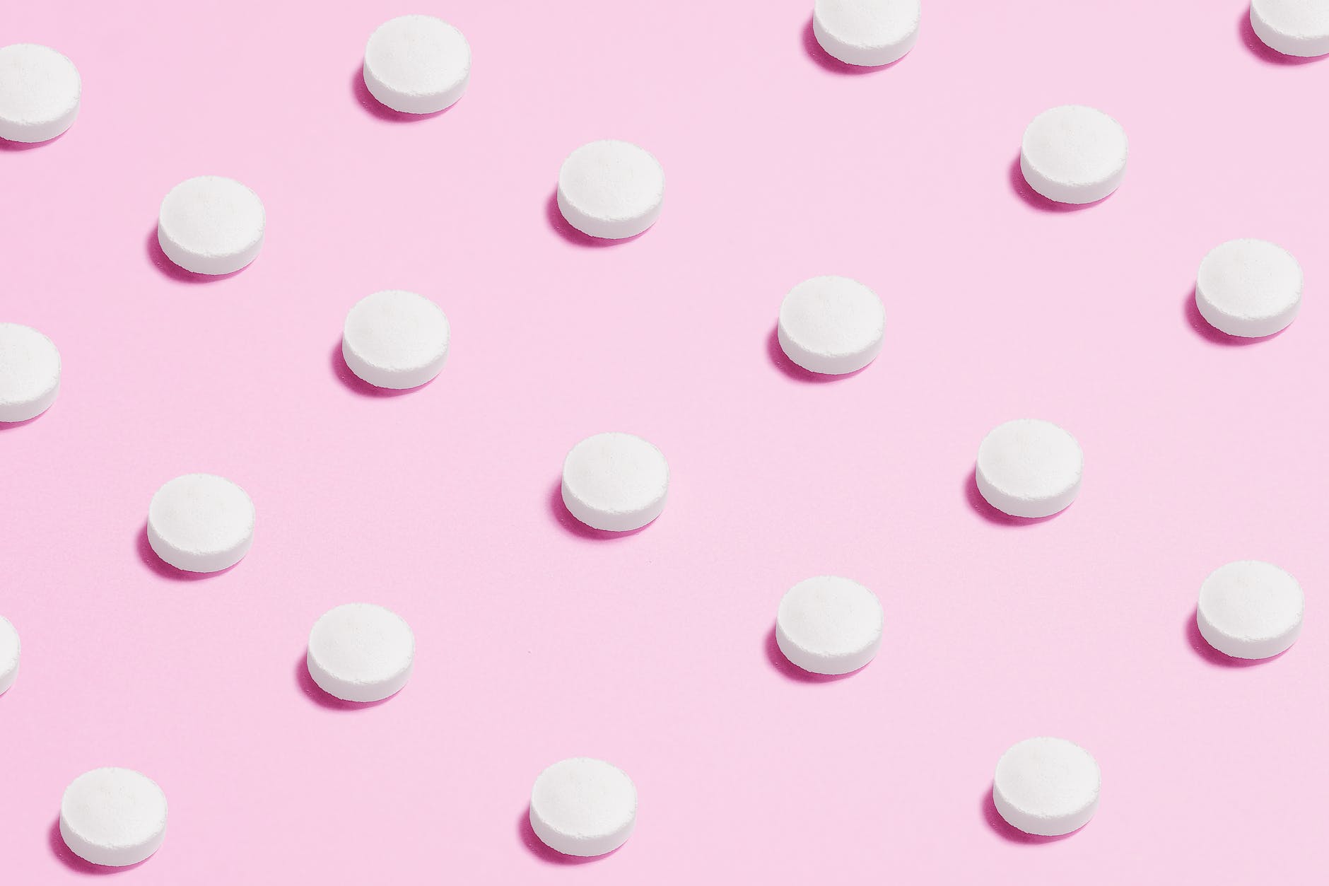 white round capsule on pink background close up photography