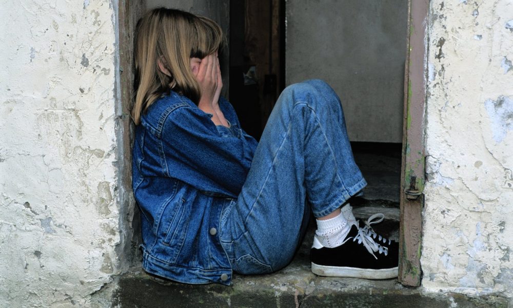 lonely girl sitting on a doorway