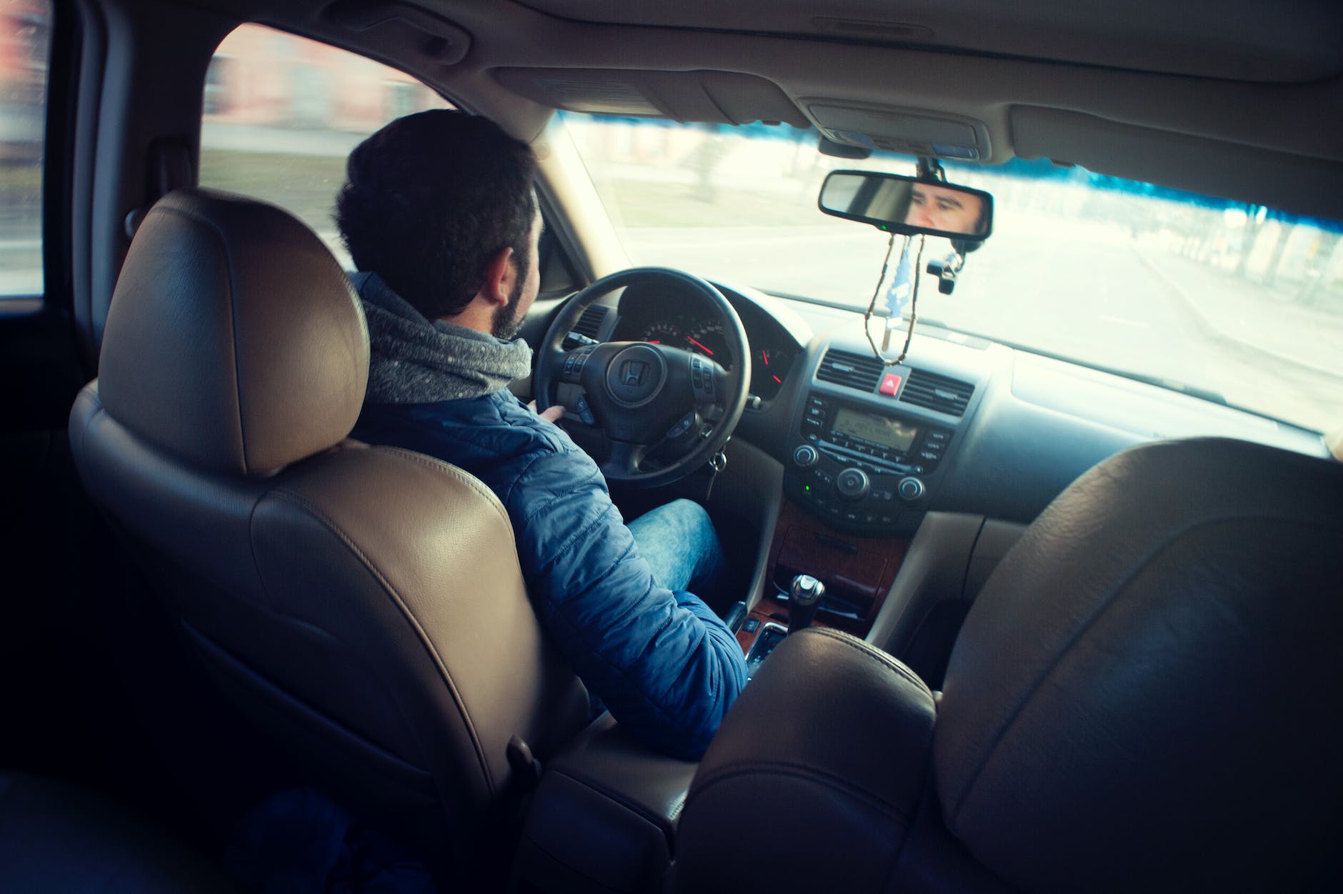 man wearing blue jacket sitting inside car while driving