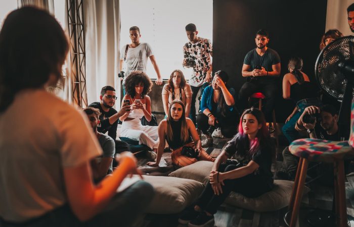 group of multiethnic people gathering around female speaker in studio