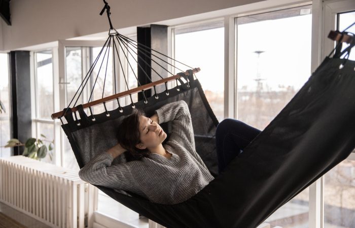 tired woman sleeping in cozy hammock in flat