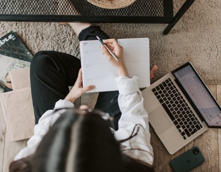faceless lady with notebook and laptop on floor at home