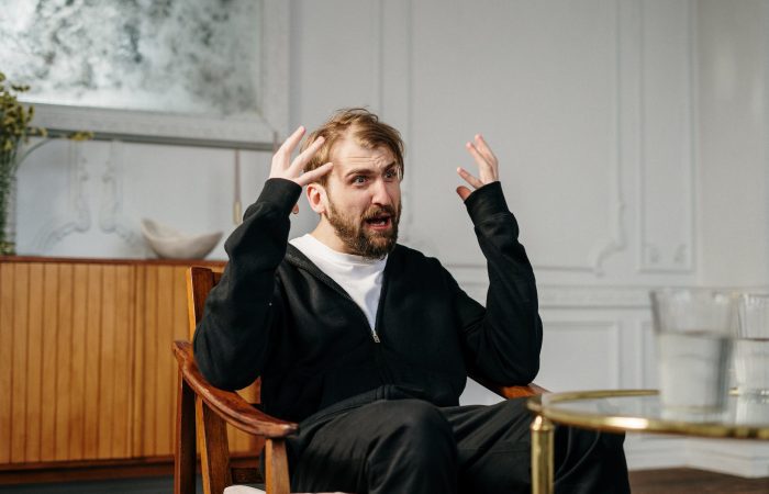 man in black suit sitting on brown wooden chair