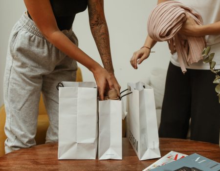 woman in black tank top and gray pants holding white paper bag