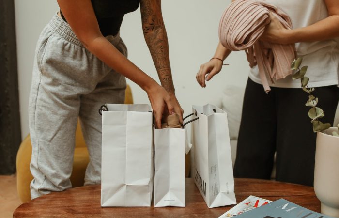 woman in black tank top and gray pants holding white paper bag