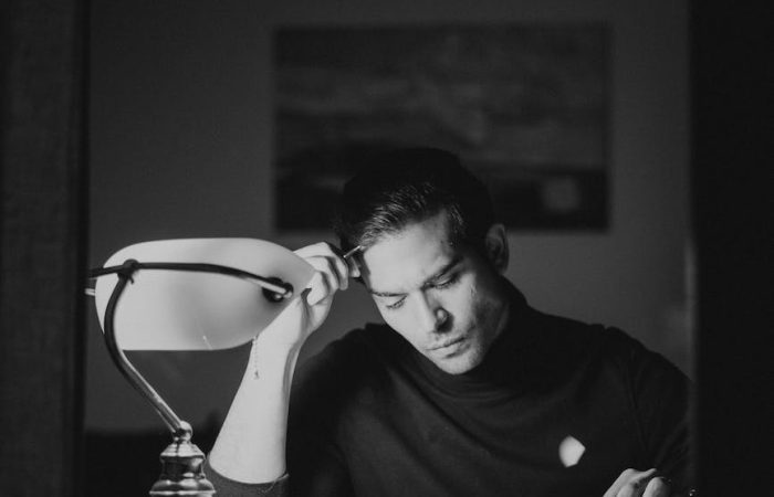 thoughtful man with books at desk in night