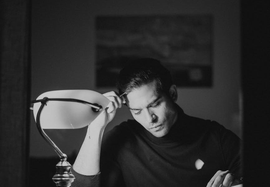 thoughtful man with books at desk in night