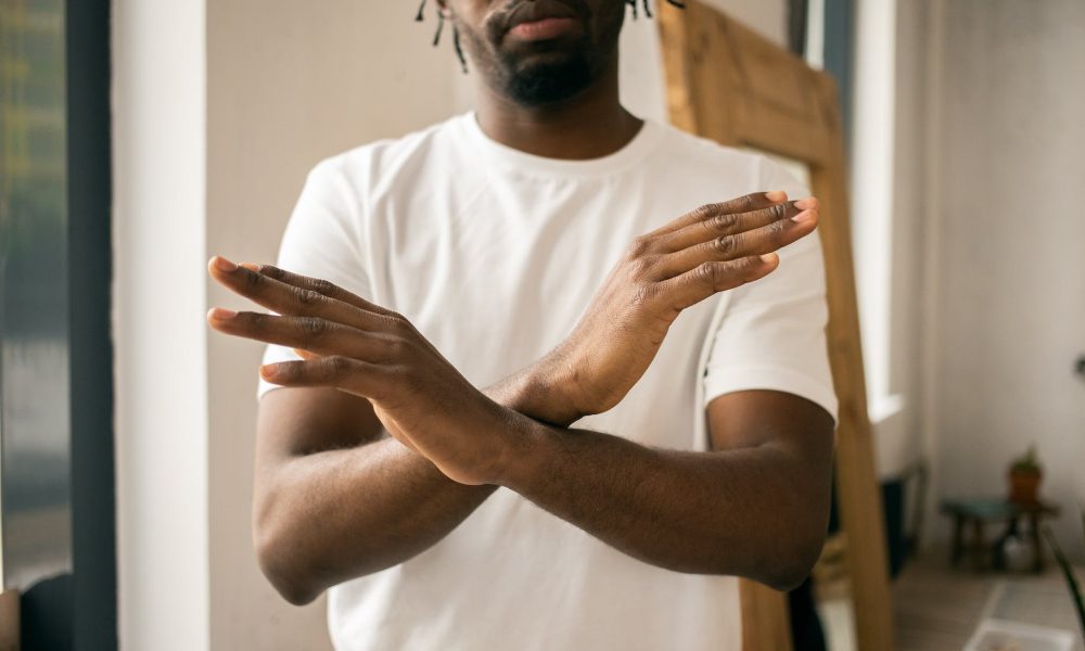 faceless black man showing stop gesture with crossed hands