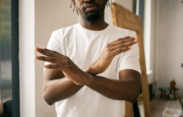 faceless black man showing stop gesture with crossed hands