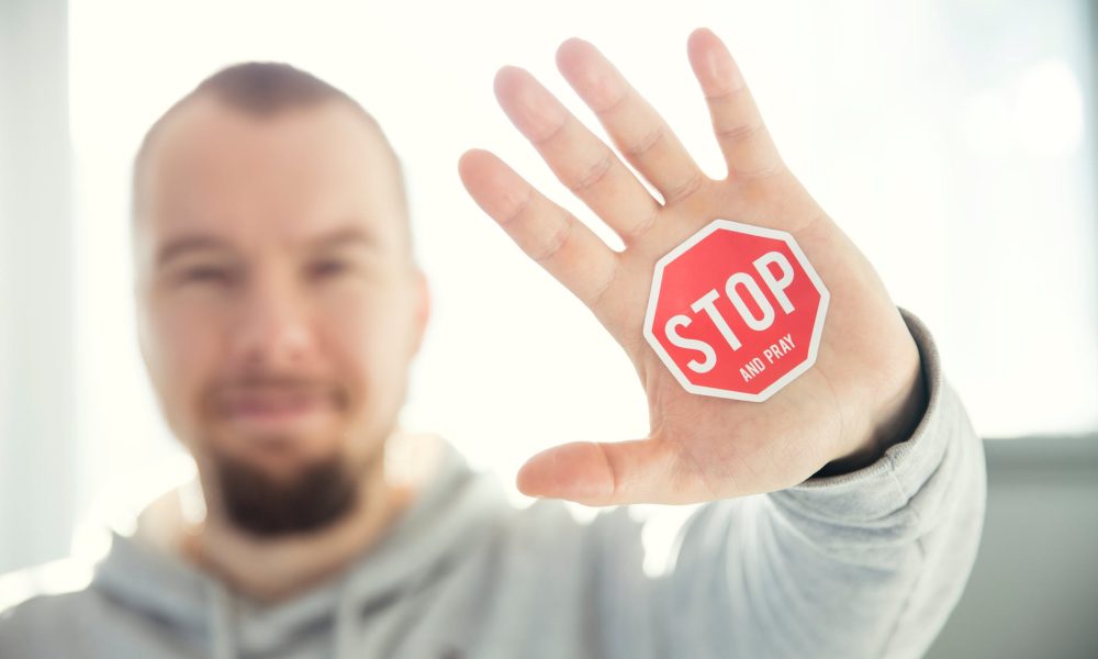 photography of a persons hand with stop signage