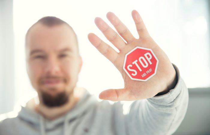 photography of a persons hand with stop signage