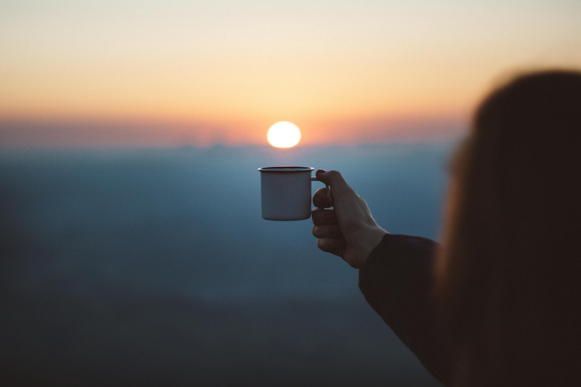 person showing white mug in focus photography