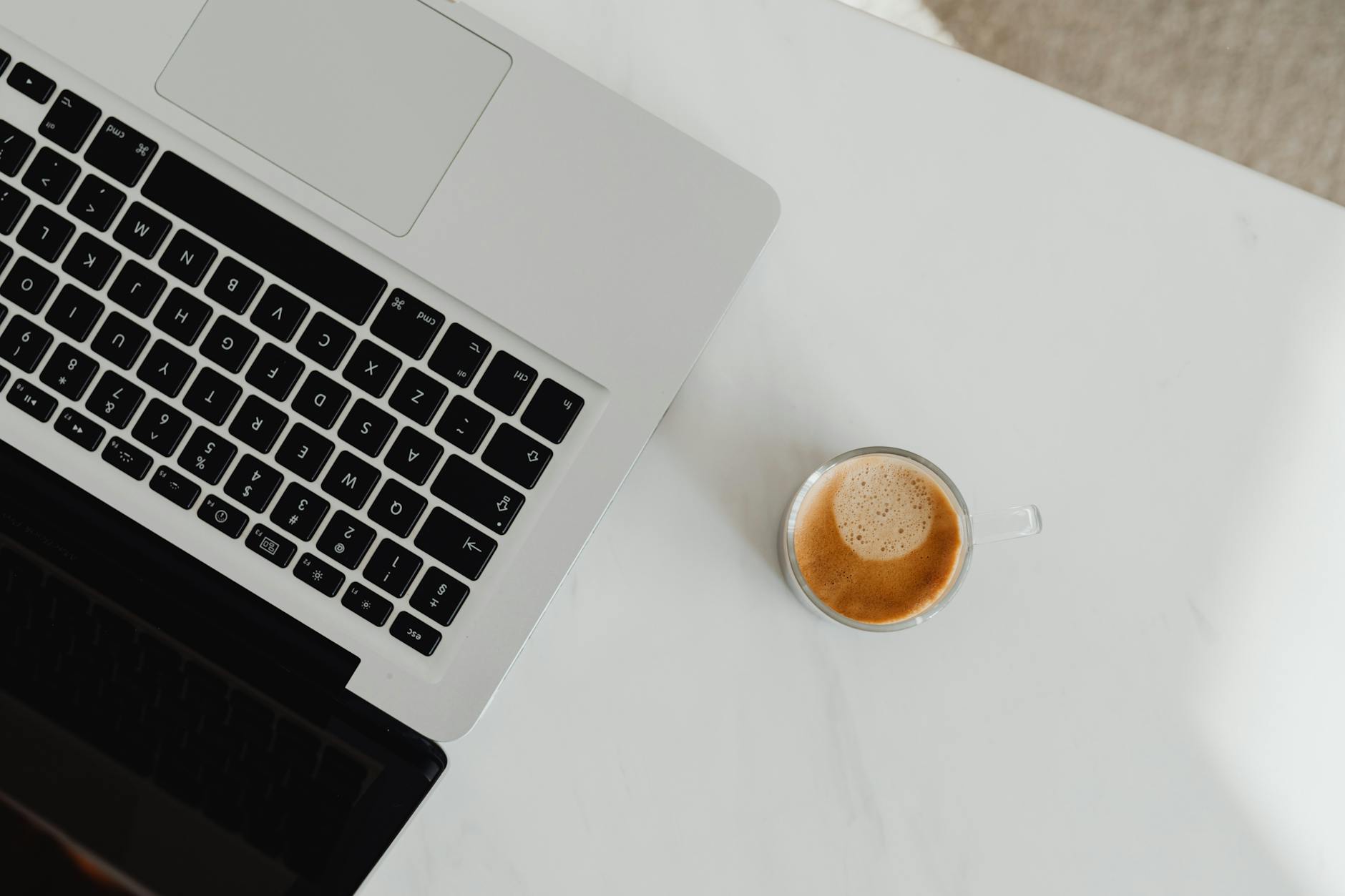 top view of an open laptop and a cup of coffe on the table