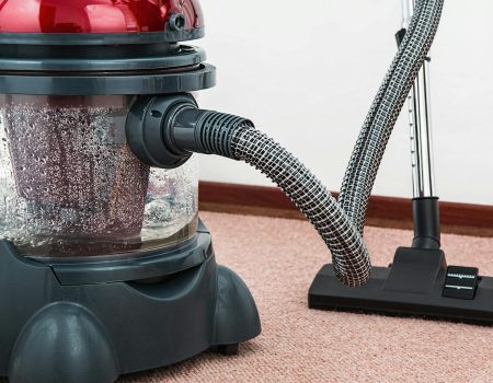 black and red canister vacuum cleaner on floor