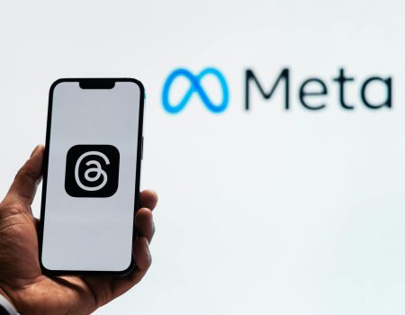 holding a smartphone with the threads app with the meta platforms logo in the background