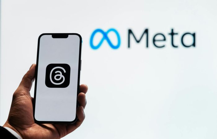 holding a smartphone with the threads app with the meta platforms logo in the background